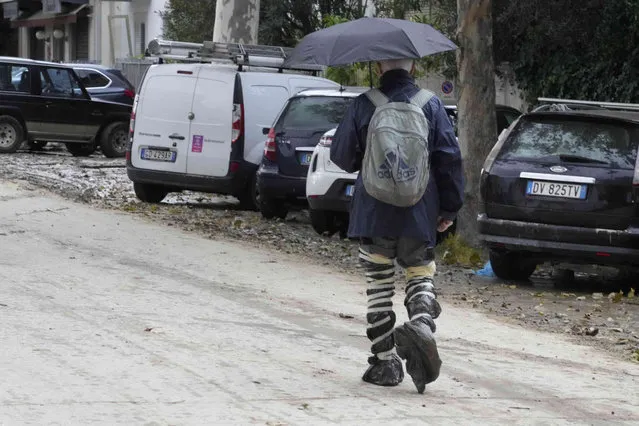 A man walks with makeshift boots in Campi di Bisenzio, in the central Italian Tuscany region, Friday, November 3, 2023. Record-breaking rain provoked floods in a vast swath of Tuscany as storm Ciaran pushed into Italy overnight Friday, trapping people in their homes, inundating hospitals and overturning cars. At least three people were killed, and four were missing. (Photo by Gregorio Borgia/AP Photo)