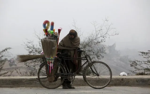 A brush salesman checks the load on his bicycle as he prepares to ride in the morning fog in Lahore, Pakistan January 25, 2016. (Photo by Mohsin Raza/Reuters)