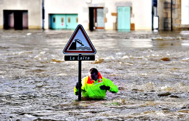 A rescuer checks a signpost in a street flooded by the coastal river Laita in the city center of Quimperle, western France on February 7, 2014. 90 houses in Quimperle were flooded by the coastal river Laitia, which is expected to rise above 4,50 meters. Northwestern France has been hit by the winter storm Qumeira on February 6 and 7, with 36 French departments rising their alert level, notably in the Finistere. (Photo by Frank Perry/AFP Photo)
