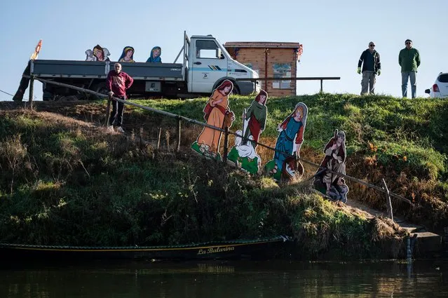Members of the association of the Friends of the Po River (Amici del Po) wait to install a Nativity Scene made of cardboard cutouts (Front R) on a boat on the Po river on December 6, 2022 in Villafranca Piemonte, near Turin. (Photo by Marco Bertorello/AFP Photo)