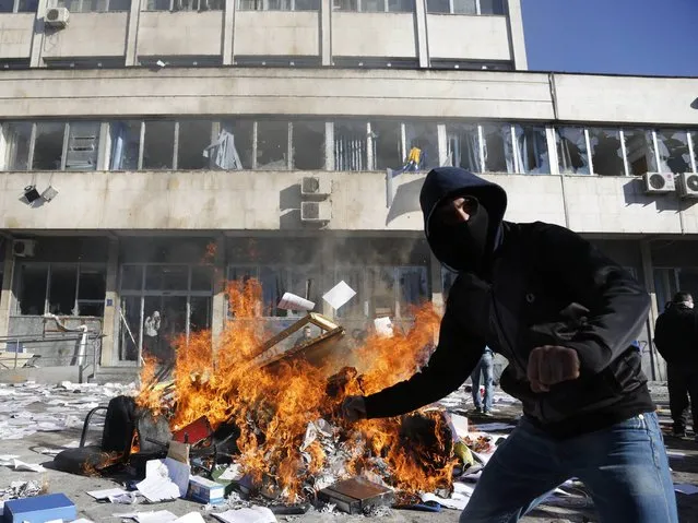 A Bosnian protester sets a local government building on fire during protests in the Bosnian town of Tuzla, on Friday, February 7, 2014. Bosnian protesters have set ablaze the local government building in Tuzla after they stormed it in rage over unemployment, rampant corruption and an overpaid political elite that appears detached from people's needs. (Photo by Amel Emric/AP Photo)