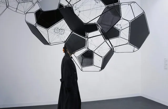In this March 24, 2016 photo, a woman walks beside an artwork by Argentina artist Tomas Saraceno at Art Basel in Hong Kong. Asia's biggest exhibition of modern and contemporary art brought together 239 galleries from 35 countries and territories in Hong Kong, which has emerged as the region's top art trading hub. (Photo by Kin Cheung/AP Photo)