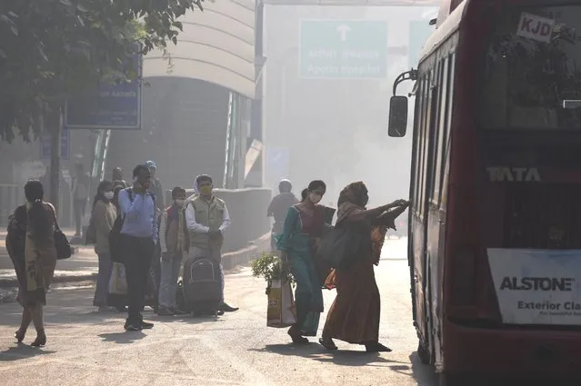 Commuters board a local transport amidst morning haze and toxic smog in New Delhi, India, Wednesday, November 17, 2021. (Photo by Manish Swarup/AP Photo)