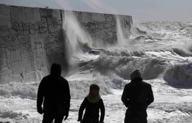 People watch waves crash against the harbour wall at Newhaven in southern Britain March 28, 2016. (Photo by Neil Hall/Reuters)