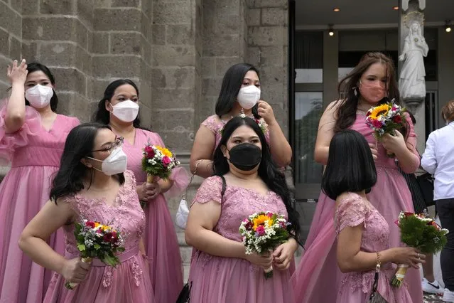 Women wearing face masks wait for the groom and bride during a wedding ceremony outside Manila's Cathedral, Philippines on Thursday, December 2, 2021. Religious activities, including weddings, have resumed with greater capacity as the government continues to ease health restrictions due to the decline of COVID-19 cases in the country while closely monitoring the new omicron virus variant. (Photo by Aaron Favila/AP Photo)