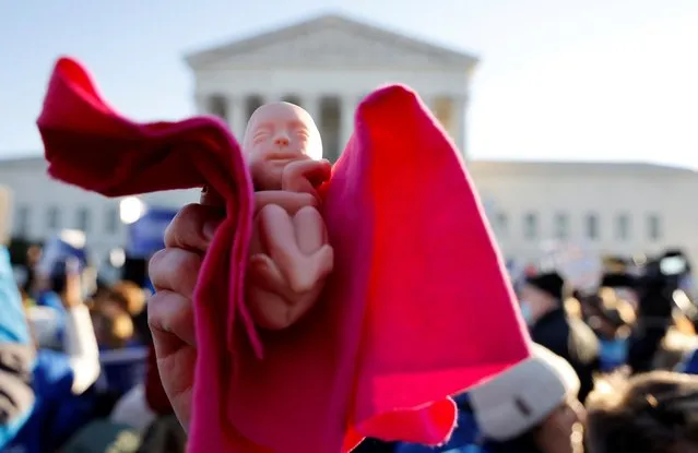 An anti-abortion rights activist holds a baby doll during a protest outside the Supreme Court building, ahead of arguments in the Mississippi abortion rights case Dobbs v. Jackson Women's Health, in Washington, U.S., December 1, 2021. (Photo by Jonathan Ernst/Reuters)