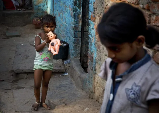 An Indian girl chews her doll as she leaves her home to play at a slum in New Delhi, India, Wednesday, May 20, 2015. (Photo by Saurabh Das/AP Photo)