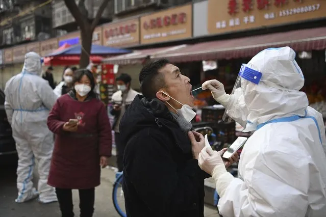 In this photo released by Xinhua News Agency, a medical worker collects swab sample from a businessman for COVID-19 test at a mobile testing site in Beilin District of Xi'an, in northwestern China's Shaanxi Province, January 2, 2022. Xi'an, an ancient capital with 13 million people is under the strictest lockdown of a major Chinese city since Wuhan was shut early last year at the start of the pandemic. (Photo by Tao Ming/Xinhua via AP Photo)