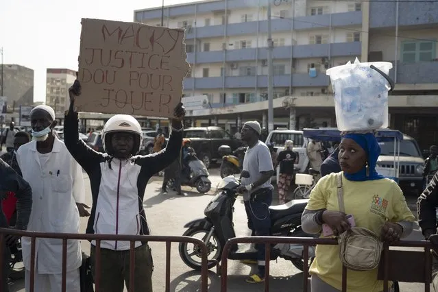 A demonstrator holds up a sign that reads in French “Macky, justice is not a game” referring to the Senegal's president Macky Sall during a protest demanding independence of the justice system in Dakar, Senegal, Friday, December 17, 2021. (Photo by Leo Correa/AP Photo)