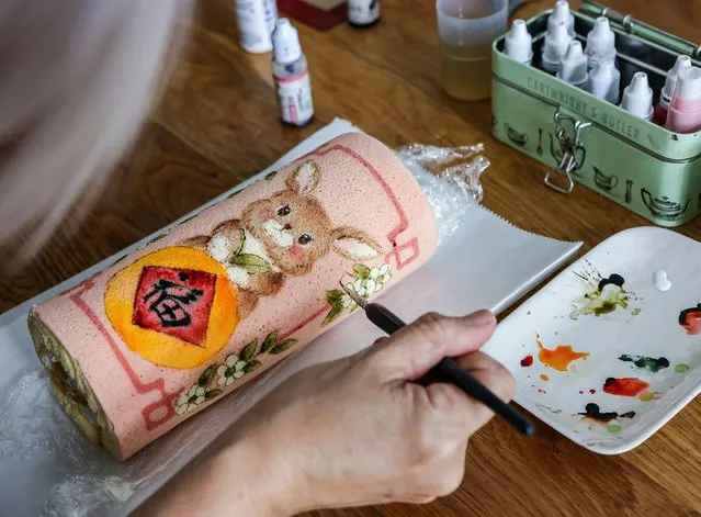 Self-taught baker Keem Ooi, 53, paints on Year of the Rabbit cakes that she sells ahead of the Lunar New Year in Kuala Lumpur, Malaysia on January 19, 2023. (Photo by Annice Lyn/Reuters)