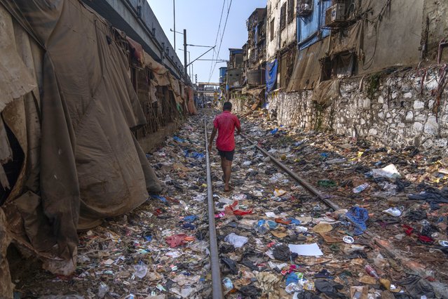 A man walks on a railway track littered with plastic and other waste materials on Earth Day in Mumbai, India, Monday, April 22, 2024. This year’s Earth Day is focusing on the threat that plastics pose to our environment. (Photo by Rafiq Maqbool/AP Photo)