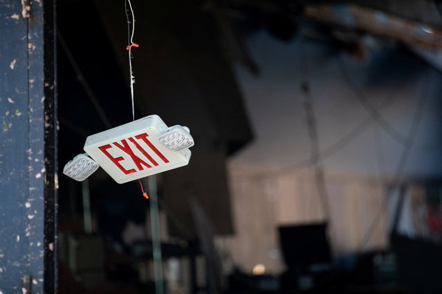 An exit sign hangs down from the ceiling of a business severely damaged after a tornado hit the area of Portage, Michigan on May 8, 2024. (Photo by Emily Elconin/Reuters)