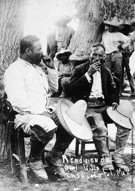 Mexican revolutionary leader Pancho Villa sits against a tree with a fellow soldier, their straw hats over their knees, following the Mexican Revolution of 1911