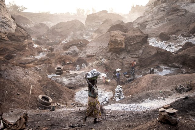 A woman carries out a pan of granite up the side of Pissy Granite Mine in the centre of Ouagadougou on January 28, 2022. (Photo by John Wessels/AFP Photo)