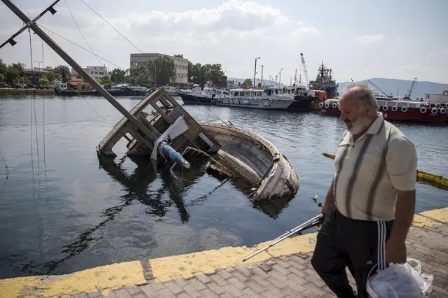 A man walks past a capsized ship at a marina in the town of Elefsina, near Athens, Greece June 30, 2015. In a poll released on July 1, 54 percent of Greeks showed that they would heed the advice of leftist Greek Prime Minister Alexis Tsipras and vote in the Greek referendum against new tough conditions for financial aid in the hope that creditors would compromise. (Photo by Marko Djurica/Reuters)