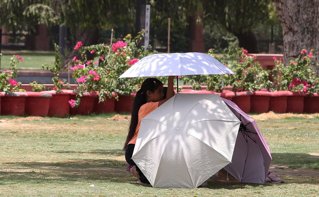 A group of tourists uses umbrellas to create some shadow to protect themselves from the bright sunlight and heat on a hot day in New Delhi, India, 30 May 2024. The India Meteorological Department (IMD) has issued a heat red alert for Delhi, Rajasthan, Haryana, Punjab, and Madhya Pradesh. The IMD Director General M Mohapatra said they are checking the temperature sensor in Delhi's Mungeshpur automatic weather station to see if it is working properly, as there were temperatures of over 50 degrees Celsius recorded on 29 May. (Photo by Harish Tyagi/EPA)