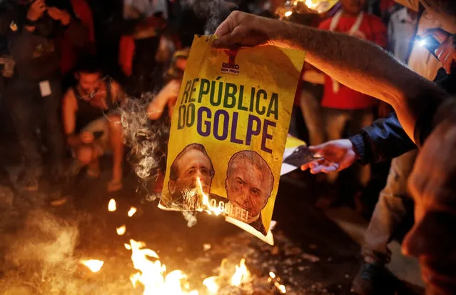 Members of Brazil's Homeless Workers' Movement (MTST) burn a poster with the images of President of the Brazilian Senate Renan Calheiros (L) and Brazil's interim President Michel Temer, after the Brazilian Senate voted to impeach President Dilma Rousseff, at Paulista avenue in Sao Paulo, Brazil, May 12, 2016. The poster reads: “Republic of the Coup”. (Photo by Nacho Doce/Reuters)