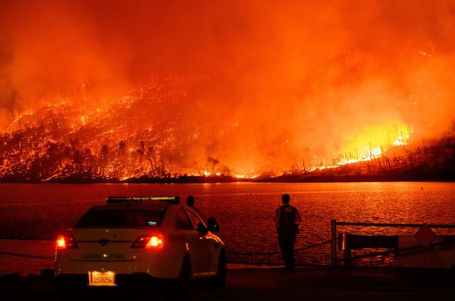 Law enforcement members watch as the Thompson fire burns over Lake Oroville in Oroville, California on July 2, 2024. A heatwave is sending temperatures soaring resulting in red flag fire warnings throughout the state. (Photo by Josh Edelson/AFP Photo)