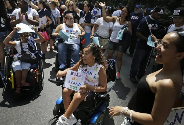 Precious Feliciano, center, and friends wave as a float passes by before the start of the inaugural Disability Pride Parade in New York, Sunday, July 12, 2015. (Photo by Seth Wenig/AP Photo)