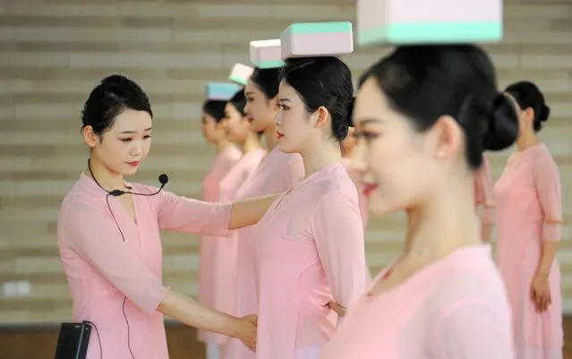 Flight attendants of Zhejiang Loong Airlines undergo rigorous posture training on March 14, 2022 in Hangzhou, Zhejiang Province of China. A total of 300 flight attendants received an etiquette training, including 13 courses for Hangzhou 2022 Asian Games, which will be held from Sept. 10 to 25, 2022 in Hangzhou. (Photo by Wang Gang/China News Service via Getty Images)