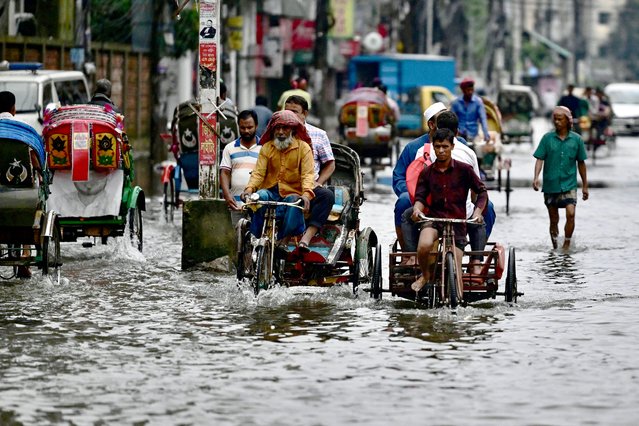 Commuters wade through a flooded street in Sylhet on June 20, 2024. Torrential rains in Bangladesh have triggered landslides burying alive at least nine people and forcing thousands to flee to higher ground, police and government officials in the low-lying nation said on June 19. In Sylhet, lashing rain and rivers swollen by flooding upstream in India also swamped heavily populated areas. (Photo by Mamun Hossain/AFP)