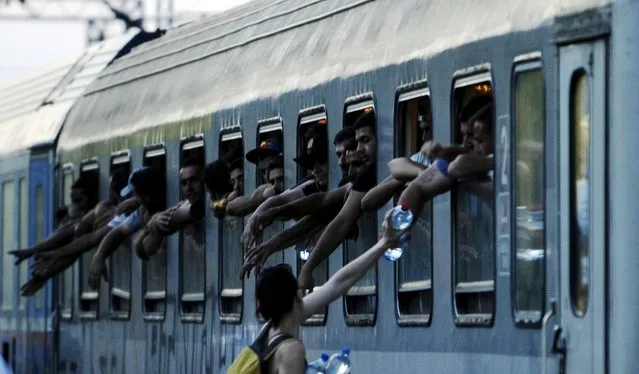 Migrants try to get water on an overloaded train at Gevgelija train station in Macedonia, near the border with Greece, on their transit route to Europe, July 19, 2015. (Photo by Ognen Teofilovski/Reuters)
