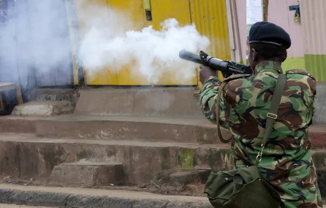 A riot police officer fires a teargas canister during a protest in Kibera Slums, Nairobi, Kenya Monday, May 23, 2016. (Photo by Sayyid Azim/AP Photo)