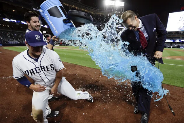 San Diego Padres' Hunter Renfroe, left, dodges energy drink dumped by teammate Austin Hedges after hitting a walk-off home run during the tenth inning of a baseball game against the Milwaukee Brewers on Monday, May 15, 2017, in San Diego. A reporter ready to interview Renfroe stands by at right. The Padres won, 6-5. (Photo by Gregory Bull/AP Photo)