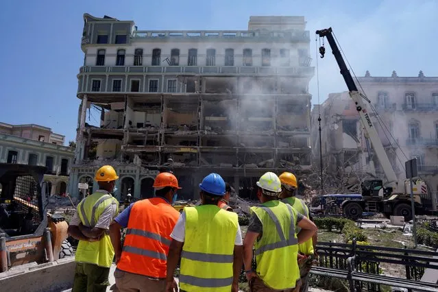 Workers look on as debris is being removed after an explosion hit the Hotel Saratoga, in Havana, Cuba on May 6, 2022. (Photo by Alexandre Meneghini/Reuters)