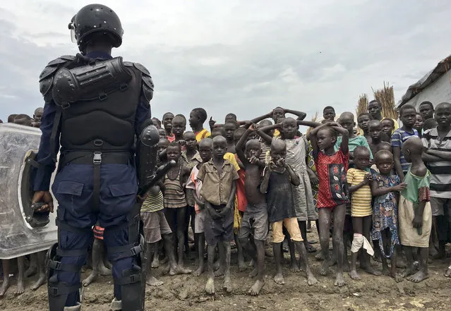 A crowd of displaced people look on as members of the U.N. multi-national police contingent provide security during a visit of UNCHR High Commissioner Filippo Grandi to South Sudan's largest camp for the internally-displaced, in Bentiu, South Sudan Sunday, June 18, 2017. Thousands of South Sudanese now live in U.N. protected camps, including eighty percent of Bentiu's population. (Photo by Sam Mednick/AP Photo)