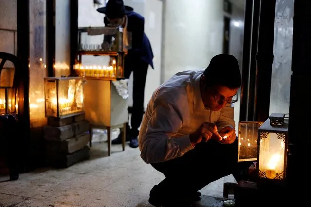 Jewish seminary students light hanukkiyot as they mark Hanukkah at the entrance to their dormitories in Bnei Brak, Israel on December 28, 2019. As sun set on Sunday, Jews across Israel marked the last night of the Hanukkah festival of lights. Hanukkah, Hebrew for “dedication”, commemorates the 2nd century BC victory of Judah Maccabee and his followers in a revolt in Judea against armies of the Seleucid Empire and the ensuing restoration of the Jewish temple in Jerusalem. (Photo by Nir Elias/Reuters)