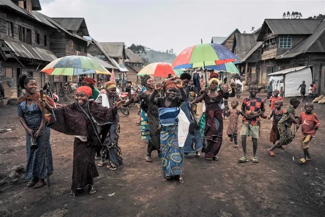 A group of women sing and dance to celebrate the birth of a child in the main street of Muheto, a three-hour motorcycle ride from Masisi Centre in the middle of mountains where armed groups regularly attack, March 28, 2022, in North Kivu province, eastern Democratic Republic of Congo. In Masisi Territory, plagued by armed conflict for nearly 30 years, the population suffers from rebel groups and army abuses. Conflicts over land and control of strategic minerals, such as coltan, fuel violence and inter-ethnic tensions. Hundreds of thousands of people have fled the clashes and looting in their villages and are crowding into camps for displaced people around the main towns. (Photo by Alexis Huguet/AFP Photo)