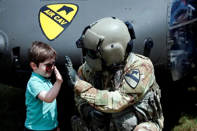 A boy high-fives a UH-60 Blackhawk helicopter pilot during an air show as part of the military exercise “Swift Response 2022 (SR22)” in Skopje, North Macedonia on May 8, 2022. (Photo by Ognen Teofilovski/Reuters)