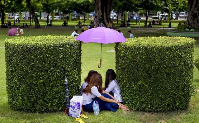 Women sit under the shade of an umbrella at a public park during a sunny afternoon in Yangon, Myanmar, on June 3, 2014. (Photo by Gemunu Amarasinghe/Associated Press)