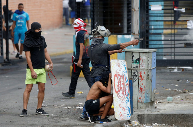 A demonstrator aims a pistol during clashes with government forces as the Constituent Assembly election was being carried out in Caracas, Venezuela, July 30, 2017. (Photo by Andres Martinez Casares/Reuters)