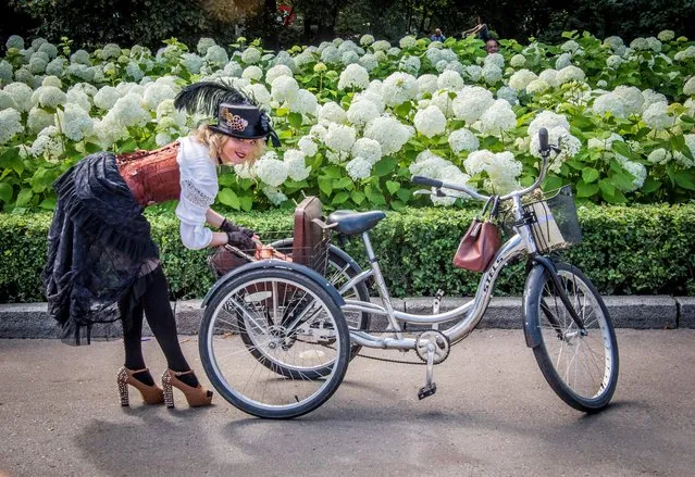 A participant in the 5th Lady on Bicycle annual festival opens her bag in the back basket of her tricycle in the Sokolniki park in Moscow on August 6, 2017. The festival's aim is to capture the city's fashionable women on vintage style bicycles. (Photo by Mladen Antonov/AFP Photo)