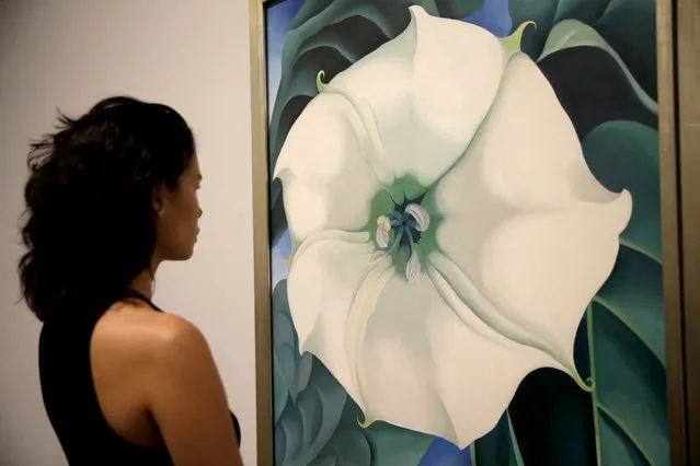 A Tate Modern representative poses for photographs next to “Jimson Weed/White Flower No.1” by American artist Georgia O'Keeffe at a press launch for her retrospective exhibition of over 100 works at the Tate Modern gallery in London, Monday, July 4, 2016. O'Keeffe is one of the iconic American artists of the 20th century, but an exhibition of more than 100 works opening this week at Tate Modern is her biggest-ever show outside the United States. (Photo by Matt Dunham/AP Photo)