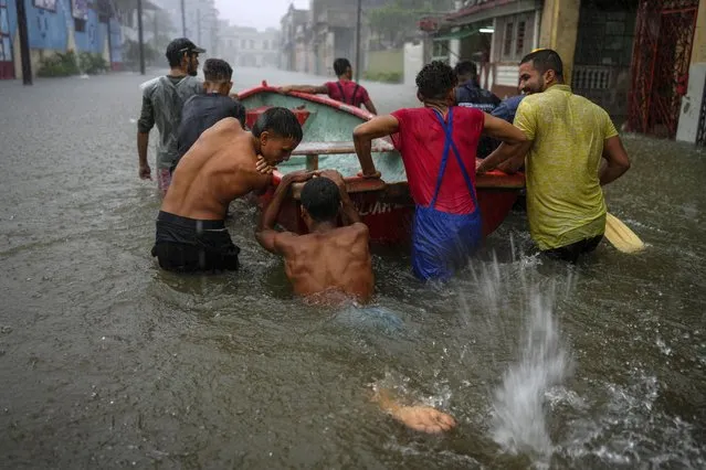 Volunteers push a boat through a street flooded by heavy rains, to go and rescue a neighbor who is unable to leave his home on his own, in Havana, Cuba, Friday, June 3, 2022. Heavy rains have drenched Cuba with almost non-stop rain for the last 24 hours as tropical storm watches were posted Thursday for Florida, Cuba and the Bahamas as the system that battered Mexico moves to the east. (Photo by Ramon Espinosa/AP Photo)