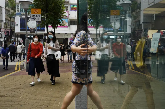 People wearing face masks walk at a street in Hong Kong Friday, March 13, 2020. For most, the coronavirus causes only mild or moderate symptoms, such as fever and cough. But for a few, especially older adults and people with existing health problems, it can cause more severe illnesses, including pneumonia. (Photo by Vincent Yu/AP Photo)