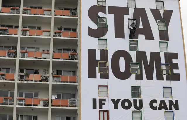 A billboard is installed on an apartment building in Cape Town, South Africa, Wednesday, March 25, 2020, before the country of 57 million people, will go into a nationwide lockdown for 21 days from Thursday to fight the spread of the new coronavirus. (Photo by Nardus Engelbrecht/AP Photo)