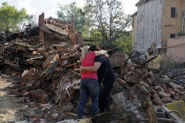 Women hug near the debris of a building that was damaged after a rocket hit the Saltivka area in Kharkiv, Ukraine, 18 August 2022. At least seven people were killed and 17 injured during the attack according to the Ukrainian State Emergency Service. A total of at least 11 people were  killed and 37 injured in the entire Kharkiv region during the overnight attack, the head of Kharkiv oblast military administration said. Kharkiv and surrounding areas have been the target of heavy shelling since February 2022, when Russian troops entered Ukraine starting a conflict that has provoked destruction and a humanitarian crisis. (Photo by Vasiliy Zhlobsky/EPA/EFE)