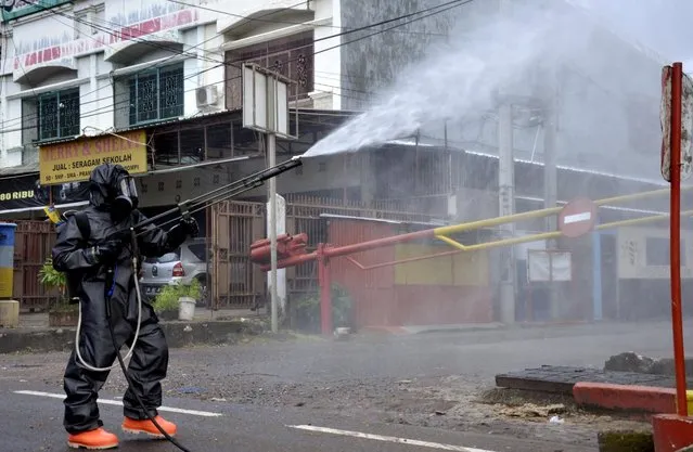 A police officer wearing a protective suit sprays disinfectant on a road amid the spread of coronavirus in Makassar, South Sulawesi province, Indonesia, March 16, 2020. (Photo by Abriawan Abhe/Antara Foto via Reuters)