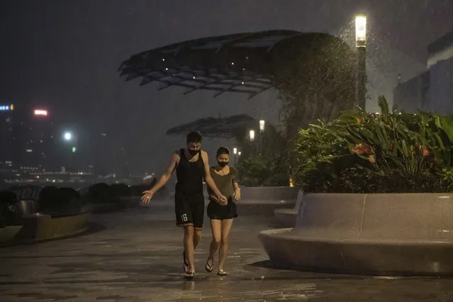 People walks on the promenade of Victoria Habour as tropical cyclone Ma-on approaches Hong Kong, Wednesday, August 24, 2022. (Photo by Anthony Kwan/AP Photo)