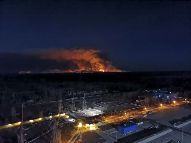 In this photo taken from the roof of Ukraine's Chernobyl nuclear power plant late Friday April 10, 2020, a forest fire is seen burning near the plant inside the exclusion zone.  Ukrainian firefighters are labouring to put out two forest blazes in the area around the Chernobyl nuclear power station that was evacuated because of radioactive contamination after the 1986 explosion at the plant. (Photo by Ukrainian Police Press Office via AP Photo)