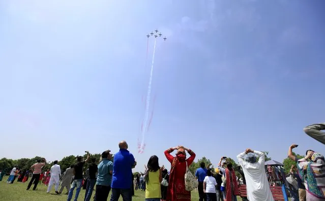 Spectators watch a performance by Pakistani jets during a ceremony marking Pakistan Defence Day in Islamabad, Pakistan, September 6, 2015. Pakistanis are celebrating the golden jubilee of Pakistan Defence Day in memory of the martyrs of the 1965 war who defended the motherland against the powerful Indian Army in the Indo-Pak war. (Photo by Faisal Mahmood/Reuters)