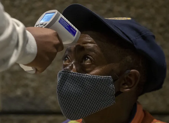 A medical staff member takes the temperature of a metro police officer during a mass screening and testing campaign for COVID-19 in Johannesburg, South Africa, Thursday, May 7, 2020. South Africa begun a phased easing of its strict lockdown measures on May 1, and its confirmed cases of coronavirus continue to increase as more people are being tested. (Photo by Themba Hadebe/AP Photo)
