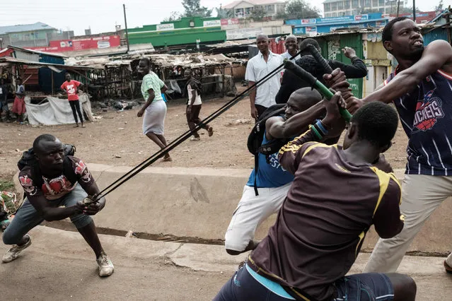 Demonstrators simulate throwing a stone toward police station, on October 16, 2017 in Kisumu, to demand the removal of officials from national election oversight body, Interim Elections and Boundaries Commission (IEBC) allegedly implicated in manipulation of the votes tally during the August 8, presidential elections. The election was annuled by the Supreme court due to massive irregularity. (Photo by Yasuyoshi Chiba/AFP Photo)