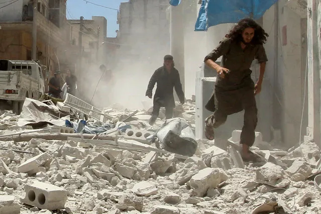 Men make their way through the rubble of damaged buildings at a site hit by air strikes in Idlib city, Syria July 20, 2016. (Photo by Ammar Abdullah/Reuters)