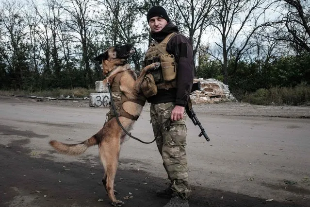 Andriy Symchuk, National Police officer of Liviv region, stands with “Bars” his sniffer dog at a checkpoint in Izyum, Kharkiv region, on September 25, 2022, amid the Russian invasion of Ukraine. (Photo by Yasuyoshi Chiba/AFP Photo)