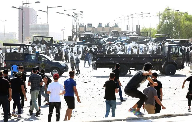 Anti-government protesters throw stones towards security forces in Tahrir Square as they try to enter the Green Zone of Baghdad, Iraq, 28 September 2022. Hundreds of Iraqis clashed with security forces as the Iraqi parliament was due to convene for the first time since deadly unrest in August and a sit-in protest by supporters of Shiite cleric and Sadrist movement leader Muqtada al-Sadr. (Photo by Ahmed Jalil/EPA/EFE)